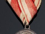 an old medal with a red and white ribbon on a black surface