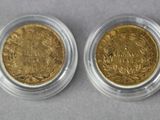 two gold coins in a clear plastic container on a gray surface
