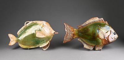 two ceramic fish sitting next to each other on a table