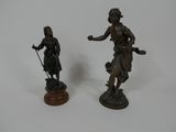 deux statues en bronze représentant une femme et un homme, posées sur un socle
