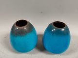 two blue vases sitting next to each other on a white surface
