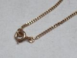 a gold chain with a heart on it on a white surface