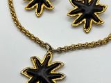two pieces of black and gold jewelry on a white surface