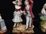 three porcelain figurines of a boy and a girl on a rock