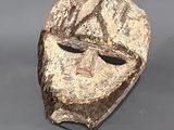 une image représentant un masque en bois posé sur un socle en métal
