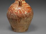 un vase marron orné de motifs sur un fond gris
