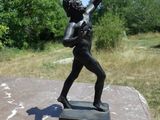 une statue représentant un garçon tenant une raquette de tennis posée sur une table