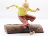 a figurine of a man jumping on a log