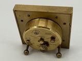 an antique brass clock sitting on top of a white surface