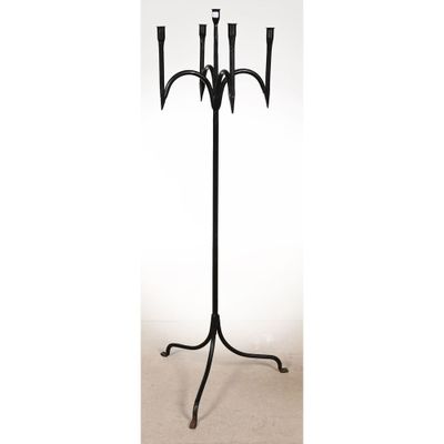 un chandelier en métal noir muni de trois bougies, posé sur un socle
