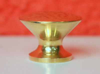 un bouton doré posé sur une table blanche, sur fond rouge