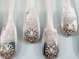 six silver spoons are lined up on a white surface