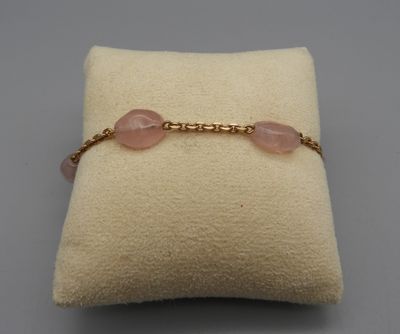 un gros plan sur un coussin sur lequel est posé un bracelet rose