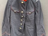Une veste grise à col rouge est suspendue à un cintre