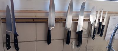 a lot of knives hanging on the wall in the kitchen