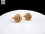 boucles d'oreilles plaquées or ornées de pierres roses sur un fond blanc