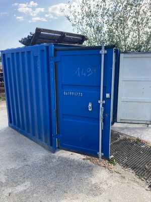 un conteneur bleu posé à côté d'une porte blanche