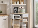 une cuisine blanche équipée d'un micro-ondes, d'une cafetière et d'étagères