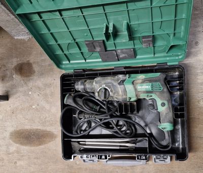 une boîte à outils verte posée par terre, contenant des outils