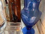 a blue vase on a shelf next to other vases