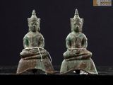 deux statues de Bouddha en bronze, assises sur une table