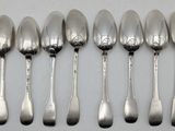 six silver spoons are lined up in a row on a white surface