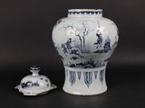 a blue and white vase sitting next to a small bell