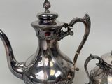 two silver teapots sitting next to each other on a table