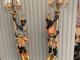 pair of black and gold figurines with a man and a woman holding a chandelier