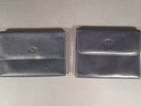 two black leather wallets sitting next to each other on a table