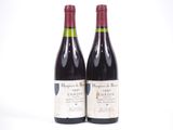 deux bouteilles de vin rouge posées l'une à côté de l'autre sur une surface blanche