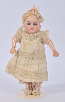 une poupée ancienne vêtue d'une robe blanche et dotée d'une tête brune