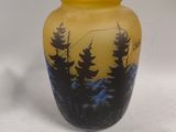 a yellow vase with trees on it sitting on a white surface