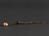 a close up of a fork and a piece of food on a black surface