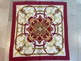a close up of a red and gold scarf on a tiled floor