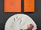 un livre orange sur lequel figure l'image d'une femme à côté d'une pile de cartes à jouer