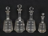 four glass decanters are lined up in a row on a black background