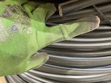 a person holding a pair of gloves on top of a pile of hoses