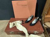 pair of black leather shoes sitting on top of a brown suitcase
