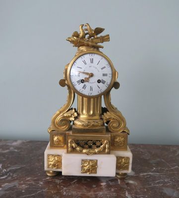 a gold clock sitting on top of a marble table