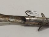 a metal object that looks like a fish on a white surface