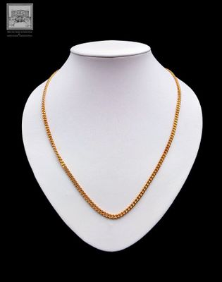 a gold necklace on a mannequin neck with a black background