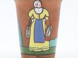 a ceramic cup with a picture of a woman in a yellow dress