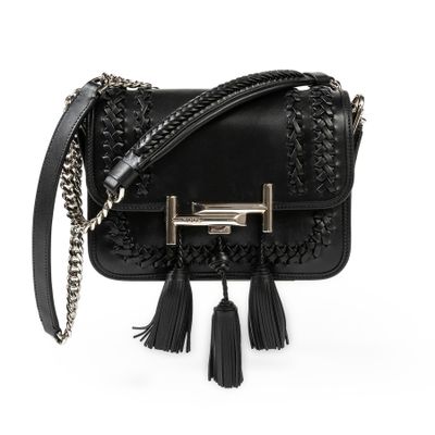 a black handbag with tassels and chains on a white background