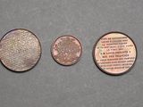 three coins are shown on a gray surface, one is a penny and the other is a penny