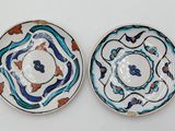 two plates with blue and orange designs on them on a white surface