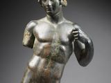 a bronze statue of a man holding a ball in his right hand