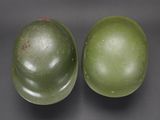 pair of green helmets sitting on top of each other on a black surface