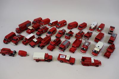 beaucoup de petits camions rouges en plastique posés sur une table blanche