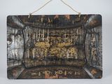 an old black and gold painted picture hanging on a wall